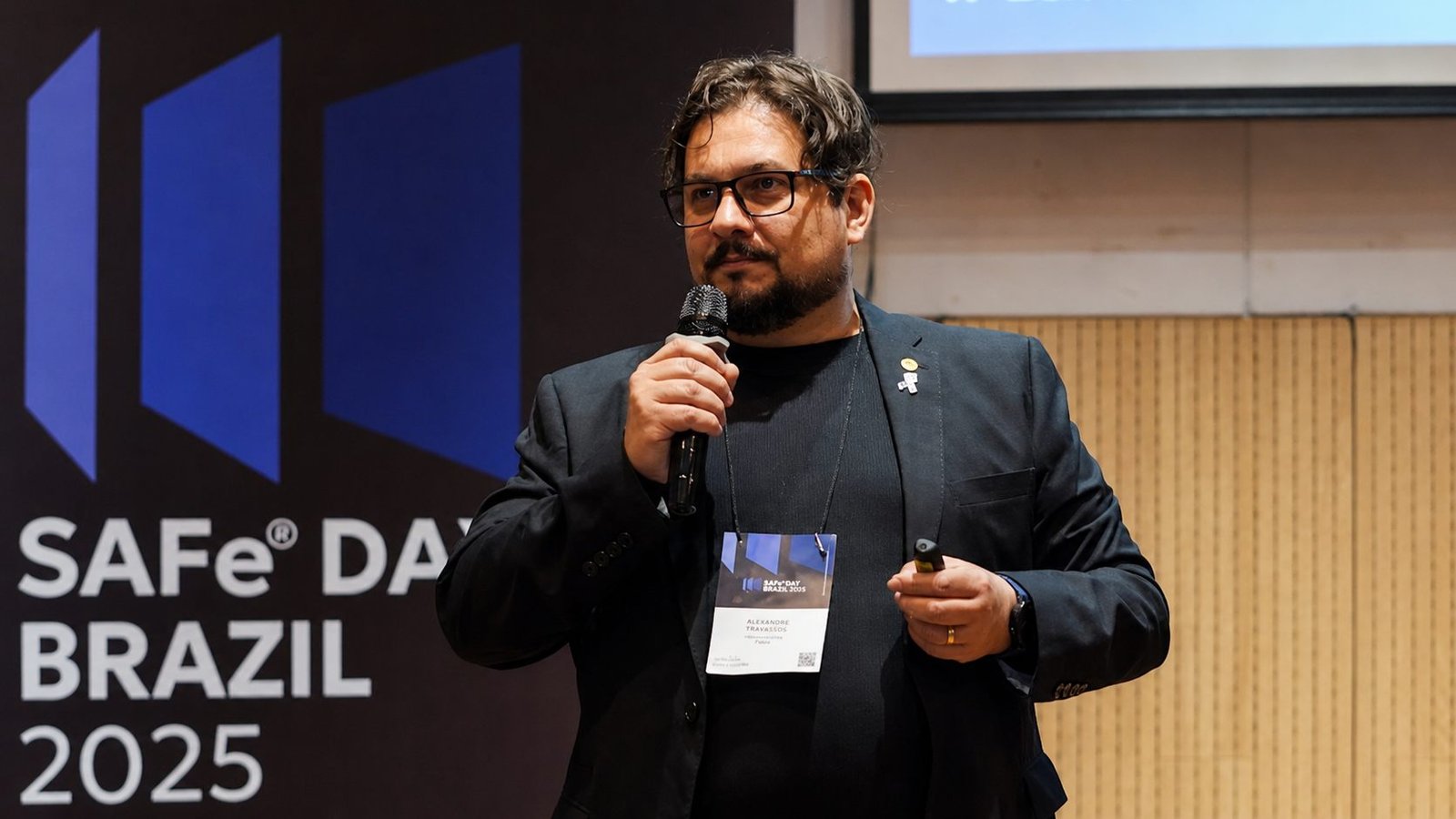 Alexandre Travassos palestrando com microfone no SAFe Day Brazil 2025.